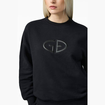 Close-up of black Goldbergh Tova sweater featuring raised GD logo embroidery on chest