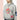 Goldbergh Tobu chest detail showing sequined crane, GOLDBERGH patch, and drawstring on heather gray hoodie