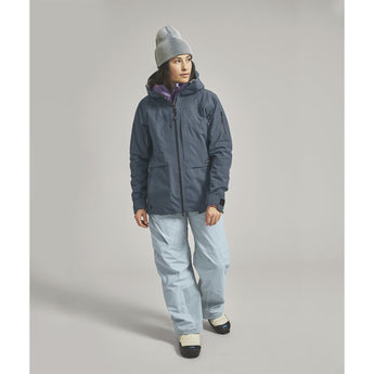 Profile view of woman wearing dark blue ORTOVOX Ravine Plus ski jacket with purple inner collar lining