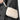 Close-up of cream faux fur pouch bag strap held against herringbone coat